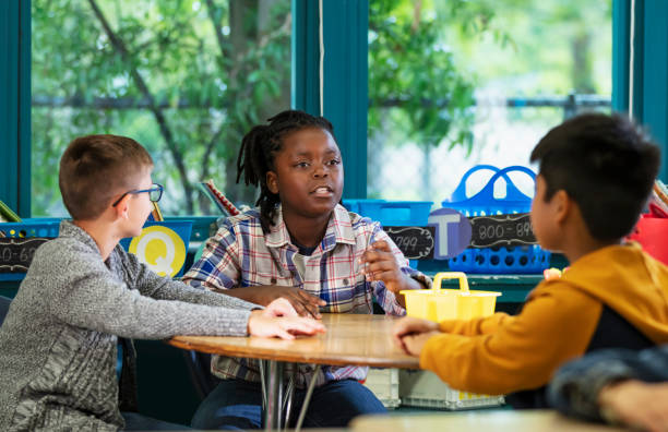 Three multiracial elementary school boys in classroom A multiracial group of three boys sitting around a table in a classroom. They are elementary students. The focus is on the African-American boy, 9 years old, who is speaking, with a serious expression. 9 stock pictures, royalty-free photos & images