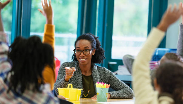 istock Teacher in classroom points to student raising hand 1457744317