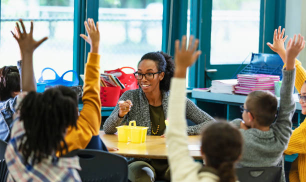 istock Teacher in classroom points to student raising hand 1457744319