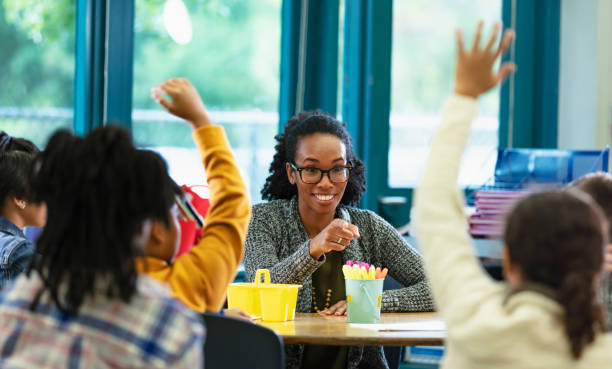 istock Teacher in classroom points to student raising hand 1457744324