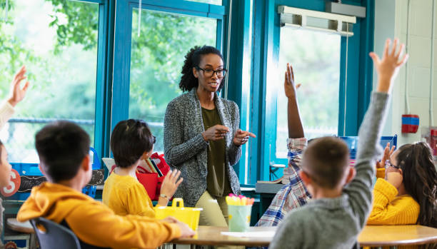 istock Teacher in classroom points to student raising hand 1457744358