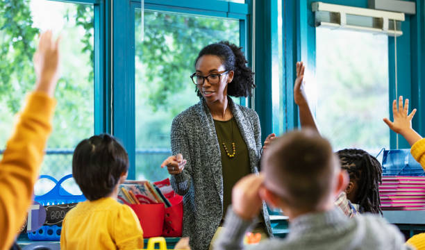 istock Teacher in classroom points to student raising hand 1457744365