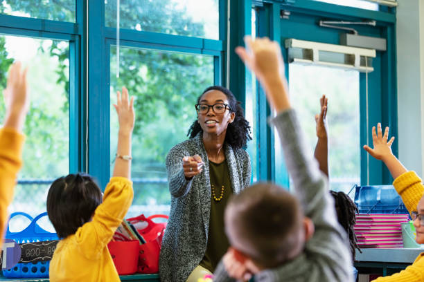 istock Teacher in classroom points to student raising hand 1457744395