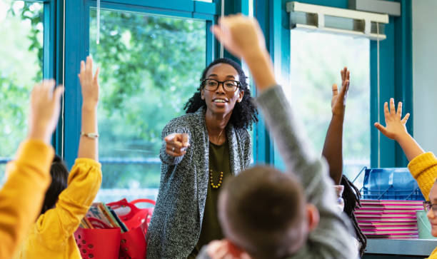 l'insegnante in classe indica lo studente che alza la mano - classroom foto e immagini stock