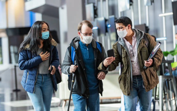 istock College students look at mobile phone, wearing face masks 1457745611