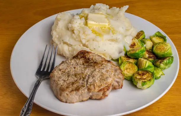 boneless pork chop served with  mashed potatoes and roasted brussel sprouts