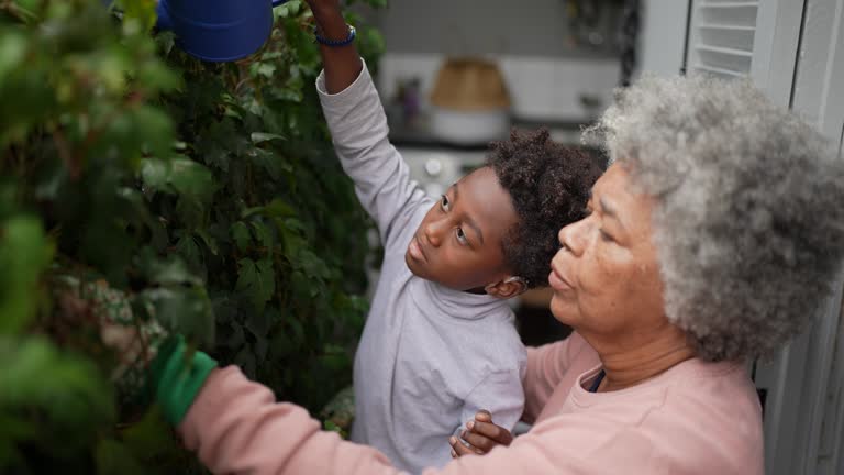 Grandmother and grandson watering the plants in the yard at home