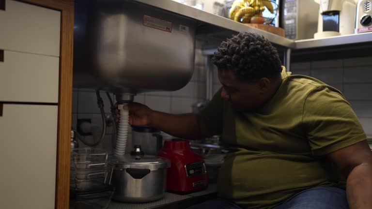 Mid adult man repairing the kitchen sink at home