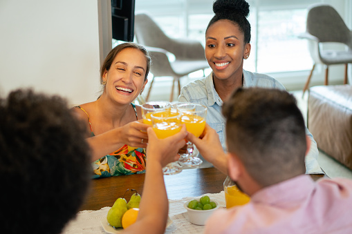 group of friends celebrating and healthy toast of juice at home