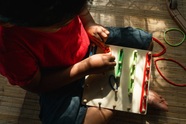 an asian little boy playing geometric nail plate, a creative game for early development and good motor skills stock photo