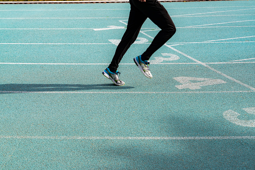 running track starting line background photo. only the legs of the runner are in the frame. numbers appear on the starting line. Shot with a full-frame camera in daylight.