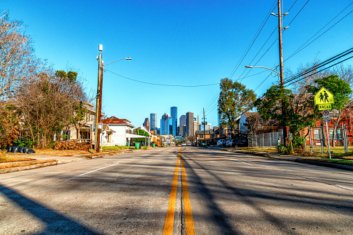 A residential street in the Midtown neighborhood of Houston, Texas leading toward the skyline of downtown.