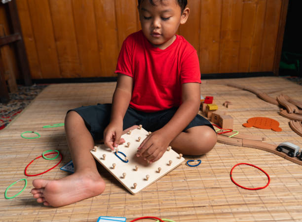 an asian little boy playing geometric nail plate, a creative game for early development and good motor skills stock photo
