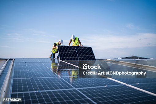 istock Two engineers installing solar panels on roof. 1457768039