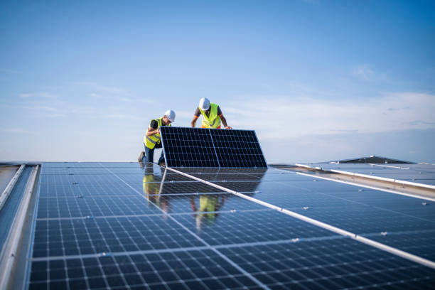 Two engineers installing solar panels on roof. Team of two engineers installing solar panels on industrial factory roof. rooftop solar stock pictures, royalty-free photos & images