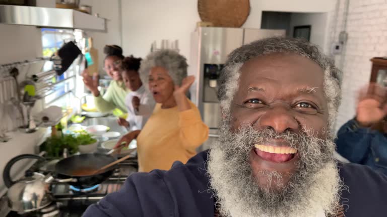 Senior man doing a video call with his family while cooking at home