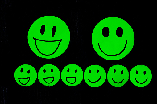 group of green paper cut smile face on black background, positive thinking, mental health assessment , world mental health day concept