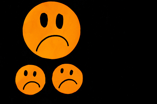 sad orange emoticons on black background concept of dissatisfaction, displeased, uncomfortable, negative evaluation...