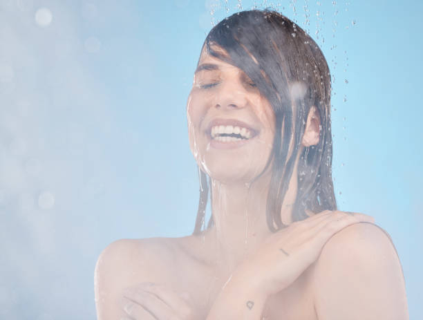 Skincare, shower and woman cleaning, happy and relax, wellness and water splash on blue background. Hair, model and girl in bathroom for beauty splash, hair care and moisture, hydration and product cuidado de la piel, ducha y limpieza de la mujer, feliz y relajación, bienestar y salpicaduras de agua sobre fondo azul. peluquería, modelo y chica en baño para salpicaduras de belleza, cuidado del cabello y humedad, hidratación y producto