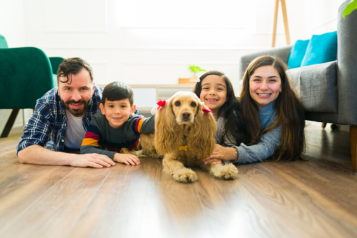 Cheerful family with young kids smiling relaxing in the living room with their beautiful cocker spaniel dog