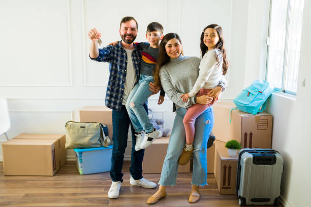 Full length of a family receiving the new house keys Caucasian dad and latin mom carrying their kids and feeling happy about being homeowners while moving into their house happy family with key of their new house stock pictures, royalty-free photos & images