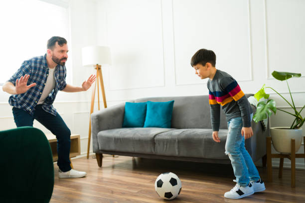 istock Fun dad and kid playing soccer at home 1457775460