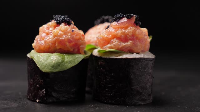 Sushi rolls rotating on black slate board