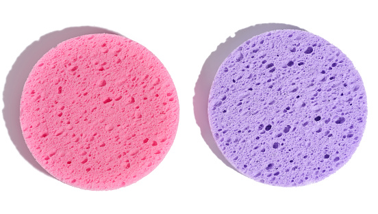 Round purple and pink makeup sponges on a white isolated background, top view