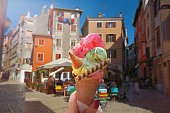 Woman hand hold  beautiful bright  sweet ice - cream cone with different flavors   held in hand