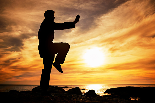 Karate, sunset and fitness with a sports man training outdoor on the beach during summer with mockup. Exercise, workout and health with the silhouette of a male athlete exercising for balance