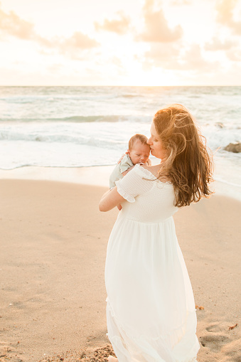 Lifestyle Newborn Family Beach Photo During a Golden Sunrise Over the Palm Beach, Florida Seashore in November of 2022