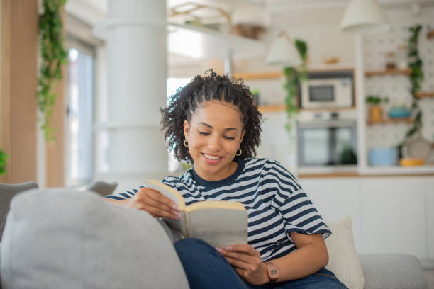istock Happy woman reading book at home 1457784646