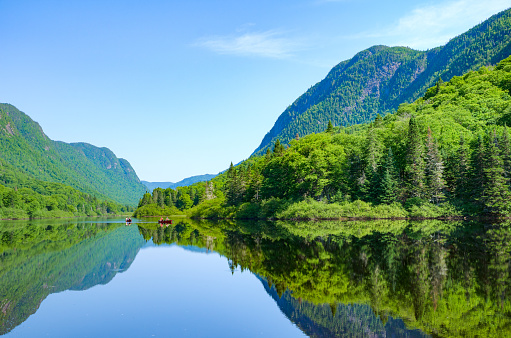 Perfect reflection in Lake Matheson surrounded by beautiful natural forest under blue sky with view to Southern Alps and Mount Cook, South Island new Zealand.