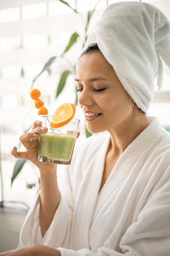 details of the face and towel on her head, young woman, care and well-being, enjoying a natural drink in the morning, health