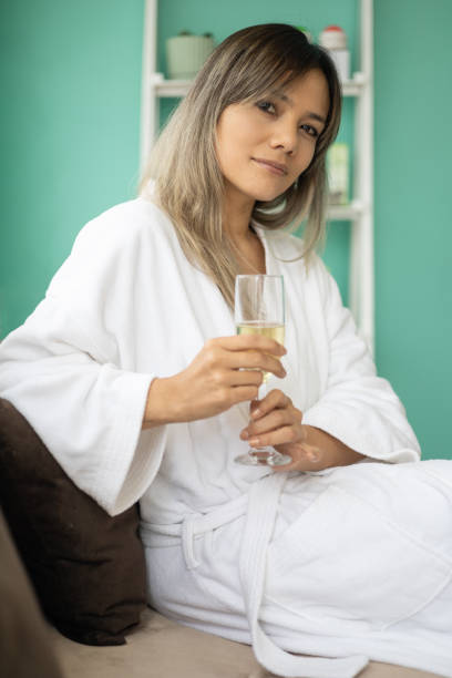 istock young beautiful woman holding a drink, dressed in comfortable bathrobe while resting 1457786529