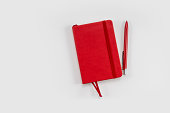 Red notebook with a pen isolated on white