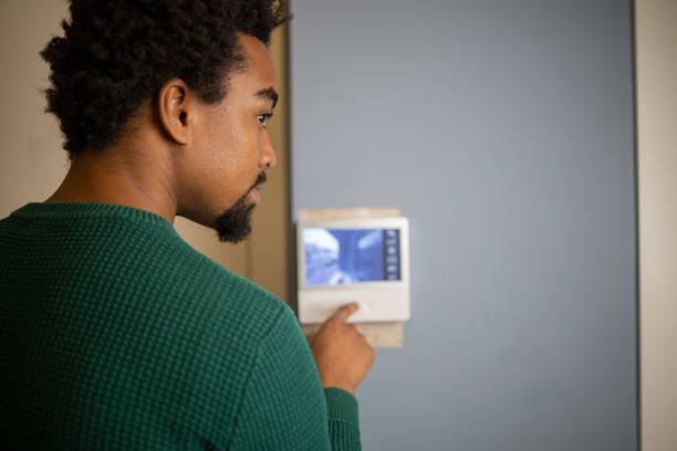 istock Young man adjusts the temperature at home with a device on the wall 1457793757