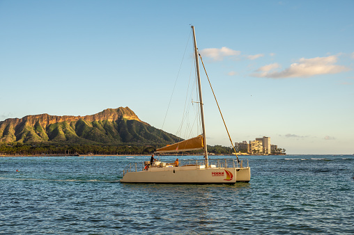 Honolulu, Hawaii - December 26, 2022: the Holokai Catamaran off Waikiki Beach as the sun drops in evening.