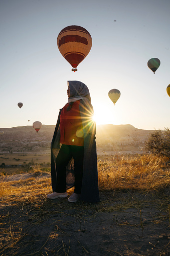 Senior woman enjoy the sunrise with view of  hot balloon in goreme