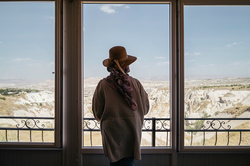 senior woman looking mountain range of goreme view from the window of restaurant