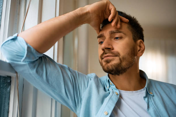 istock Thoughtful man looking through the window at home. 1457799356