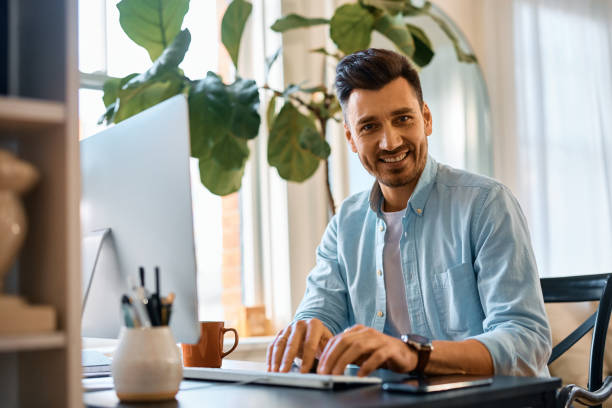 istock Happy businessman working on desktop PC at home and looking at camera. 1457799390