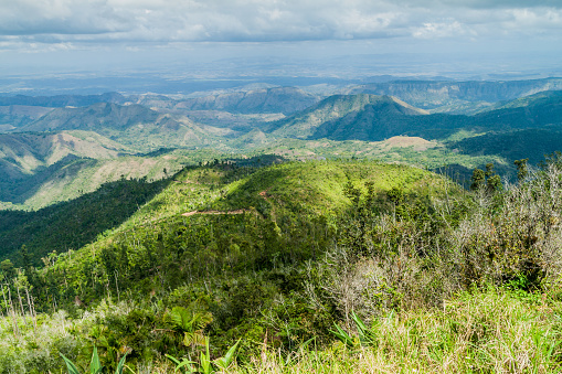 Framed aerial view from the plateau to the valley and adjacent mountains covered with white clouds, blue sky, Barichara, Colombia
