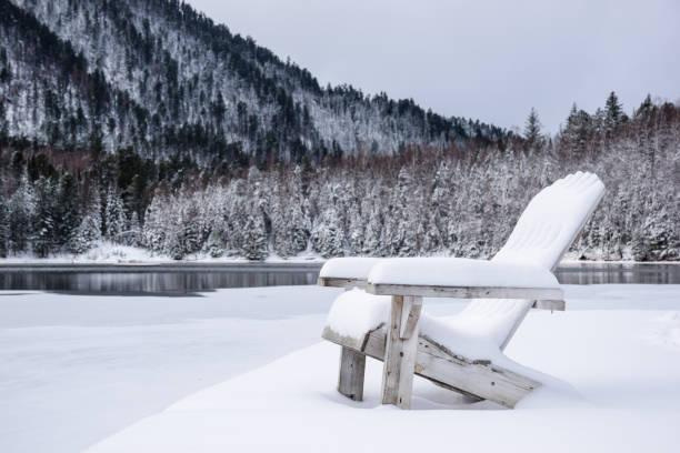 une station balnéaire sur le lac en hiver. des chaises en bois dans la neige au bord d’un lac gelé. une chaise en bois dans la neige au bord du lac sur fond de montagnes. chaise enneigée au bord du lac en hiver. - nobody tranquil scene nature park photos et images de collection
