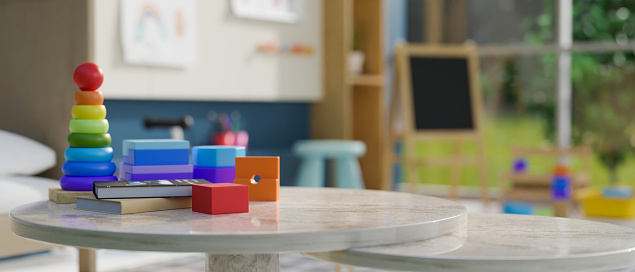 Kid toys and book on tabletop over blurred background of creative and colorful kindergarten classroom or kids playroom. 3d render, 3d illustration