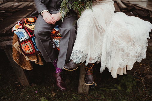 Bride and groom sitting outdoors on a afghan blanket