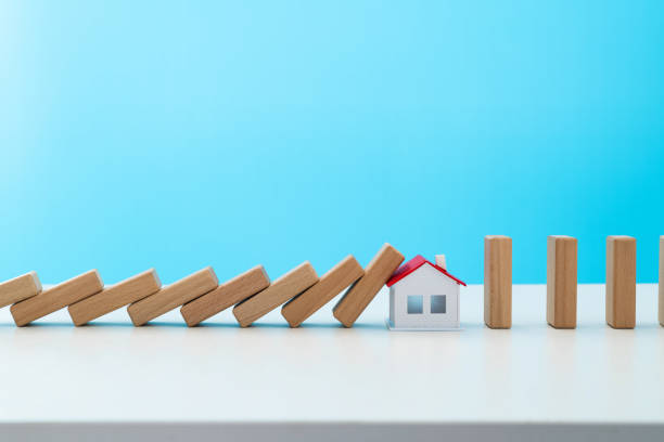 istock Wooden dominos falling to a model house 1457819075