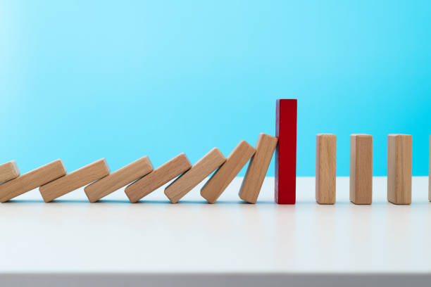istock Red wooden block stop other falling dominos 1457819084