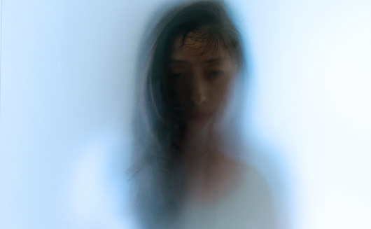 Woman face behind frosted glass.