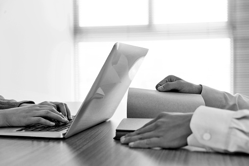 Woman using laptop and man reading book.